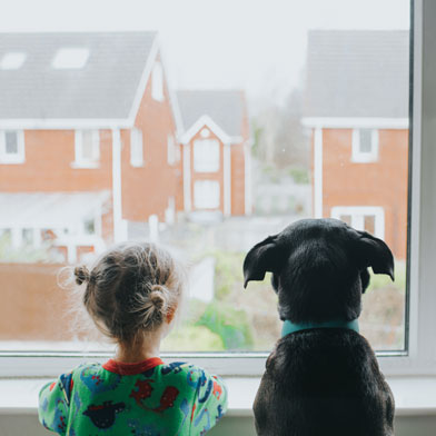 child and dog looking out a window