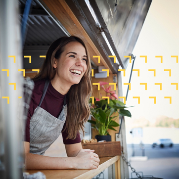 A woman leaning on a food truck window, smiling