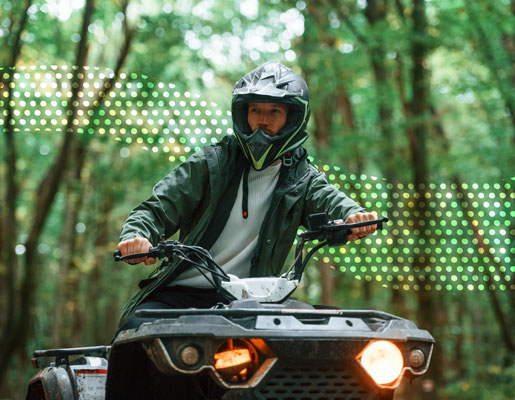 A man riding an ATV through the woods