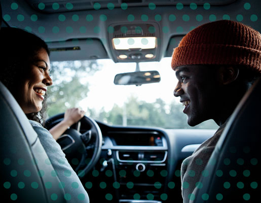 A couple looking at each other inside a car, smiling