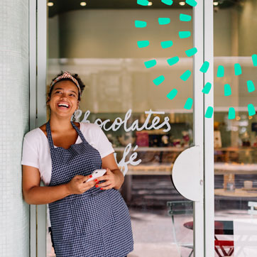 Woman standing in front of a cafe, smiling