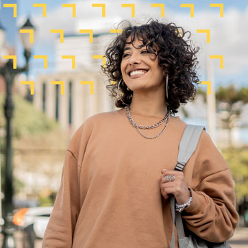 Curly-haired woman with backpack smiling at something in the distance