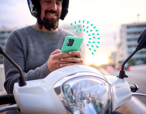 Man on a motorcycle smiling while looking at a mobile phone