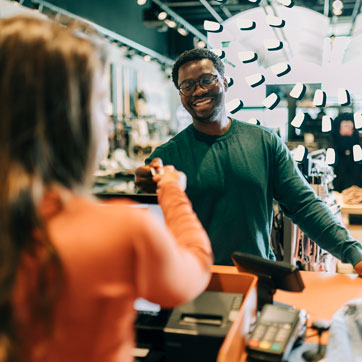 A man, smiling, paying with a credit card