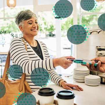 A woman, smiling, paying with a credit card
